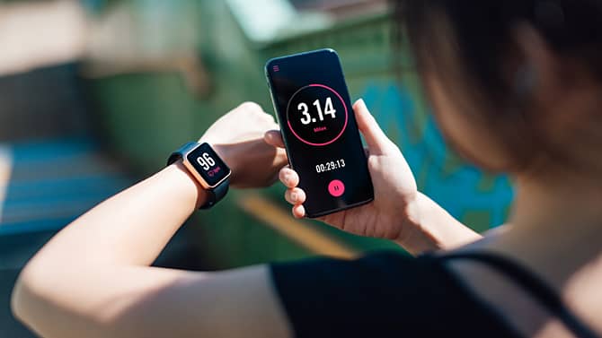 Akıllı telefonunda ve akıllı saatinde fitness uygulaması kullanan bir kadın. Fitness izleme uygulamaları, teknolojinin sağlık üzerindeki pozitif etkilerine verilebilecek örneklerden biridir.